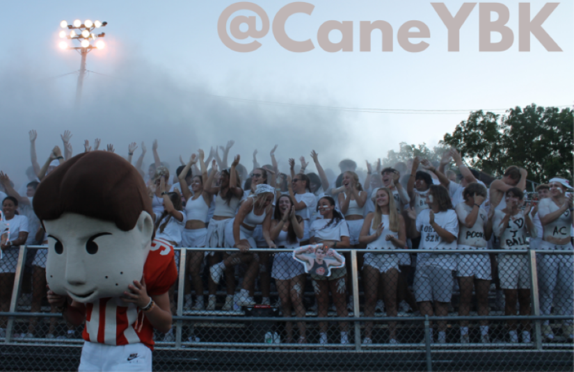 kids in stands cheering with mascot and "@CaneYBK"